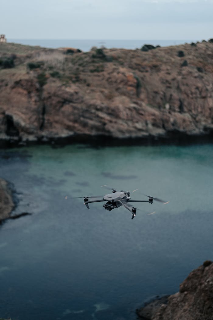 A drone flies over a rocky coastal landscape, capturing stunning aerial views.