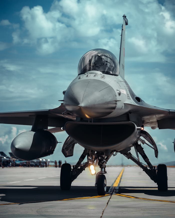 pexels-photo-15127547 Front view of a fighter jet on a runway under a bright blue sky, showcasing military aviation.